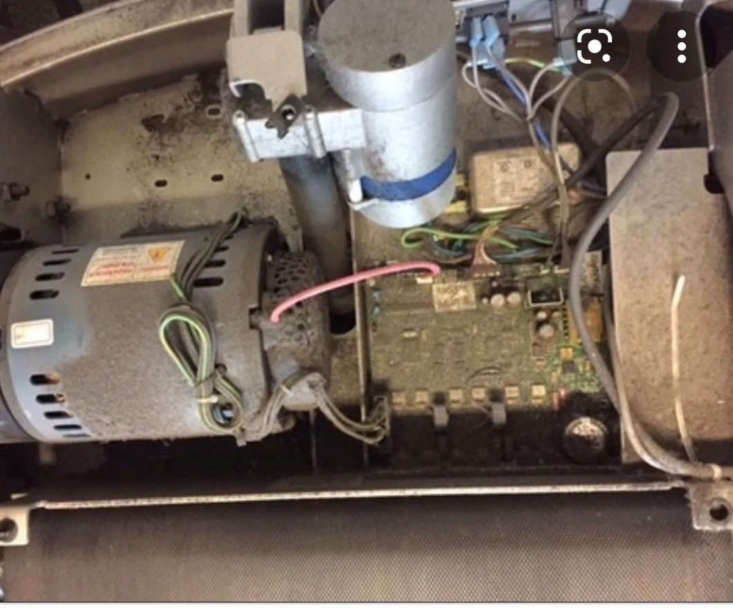 Dusty interior of a treadmill motor and wiring component setup with various cables.